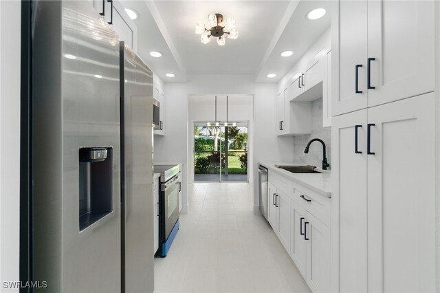 kitchen with decorative backsplash, appliances with stainless steel finishes, sink, and white cabinetry