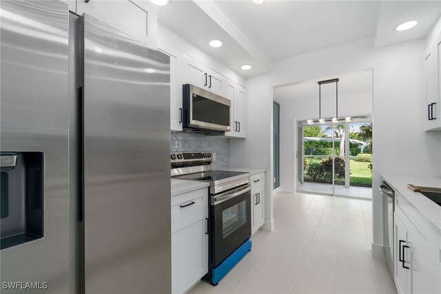 kitchen with appliances with stainless steel finishes, backsplash, white cabinets, and hanging light fixtures