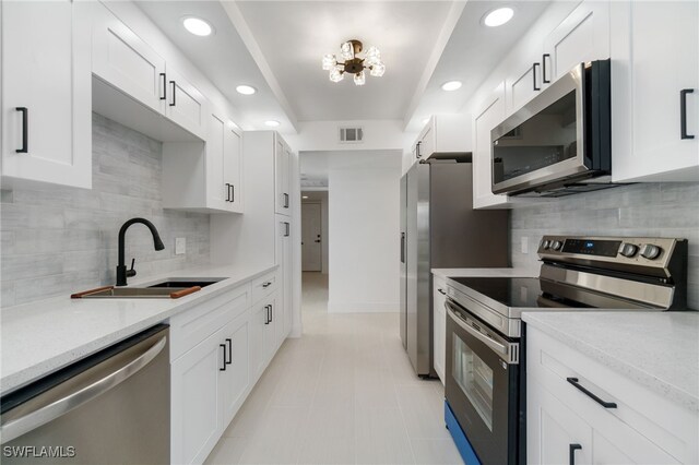 kitchen featuring light stone countertops, sink, stainless steel appliances, and white cabinetry