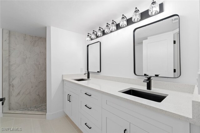 bathroom featuring vanity, a tile shower, and tile patterned flooring