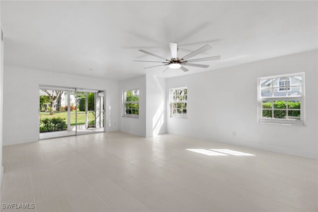 empty room with ceiling fan and a wealth of natural light