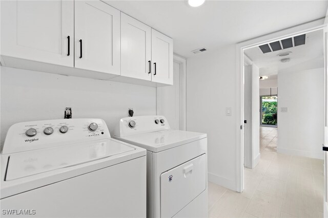 washroom featuring cabinets and washer and clothes dryer