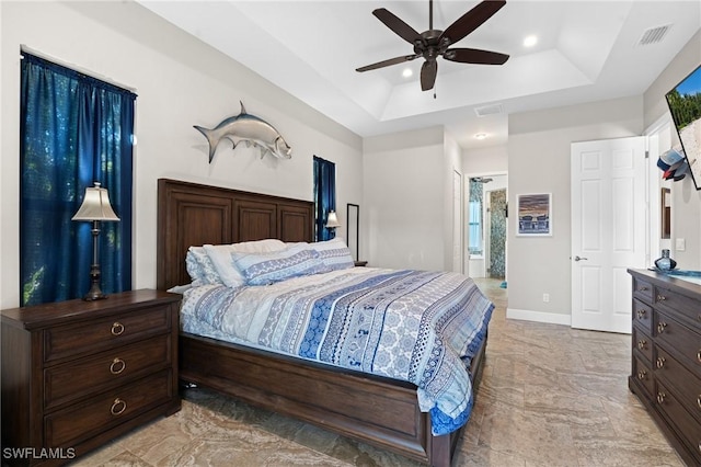 bedroom featuring baseboards, visible vents, a raised ceiling, a ceiling fan, and ensuite bath