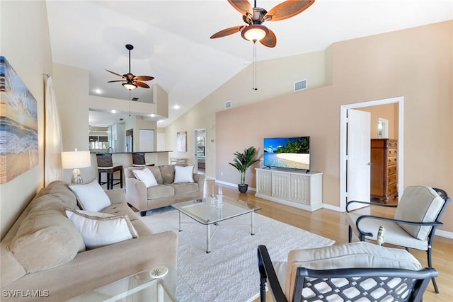 living room with ceiling fan, lofted ceiling, and light hardwood / wood-style floors