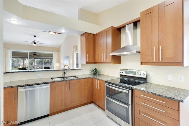 kitchen featuring wall chimney exhaust hood, stainless steel appliances, stone countertops, and sink