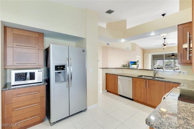 kitchen featuring sink, appliances with stainless steel finishes, kitchen peninsula, stone counters, and ceiling fan