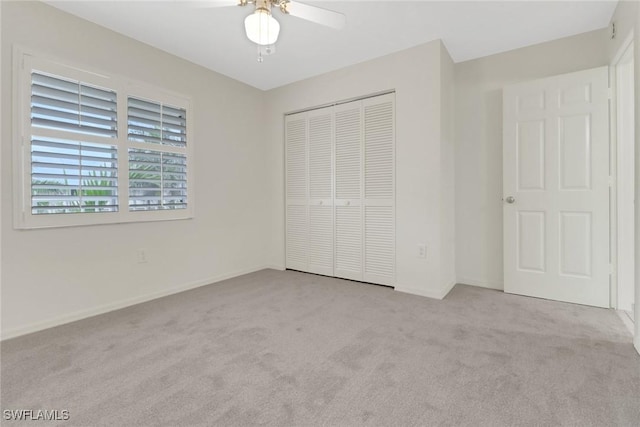 unfurnished bedroom with ceiling fan, light colored carpet, and a closet