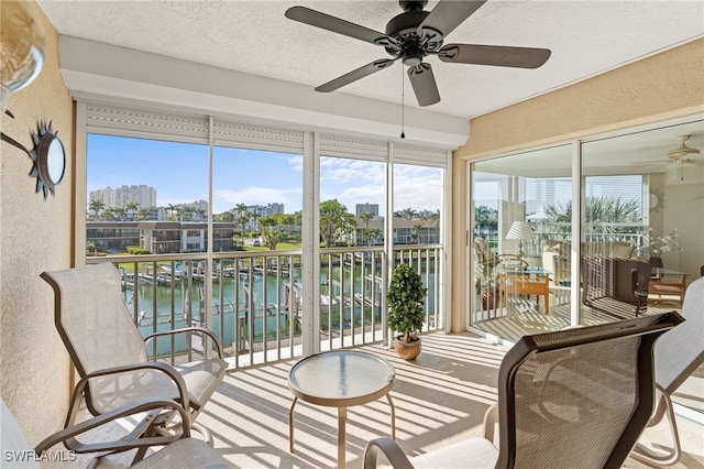 sunroom featuring ceiling fan, plenty of natural light, and a water view