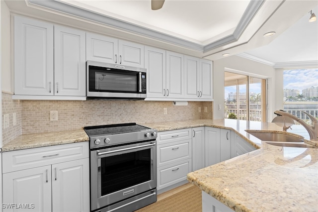 kitchen with decorative backsplash, ornamental molding, stainless steel appliances, sink, and white cabinets