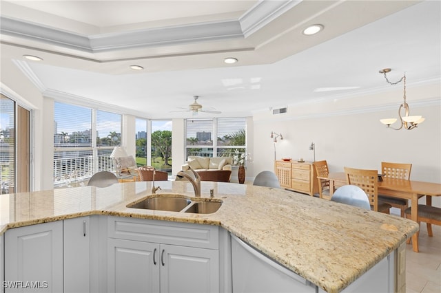 kitchen with pendant lighting, ceiling fan with notable chandelier, sink, ornamental molding, and white cabinetry