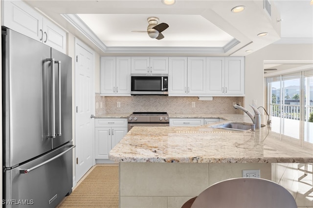 kitchen with sink, stainless steel appliances, a kitchen breakfast bar, light stone counters, and white cabinets