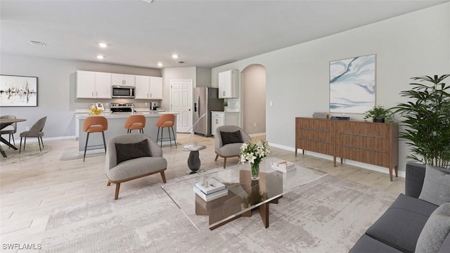 living room featuring arched walkways, recessed lighting, visible vents, and baseboards