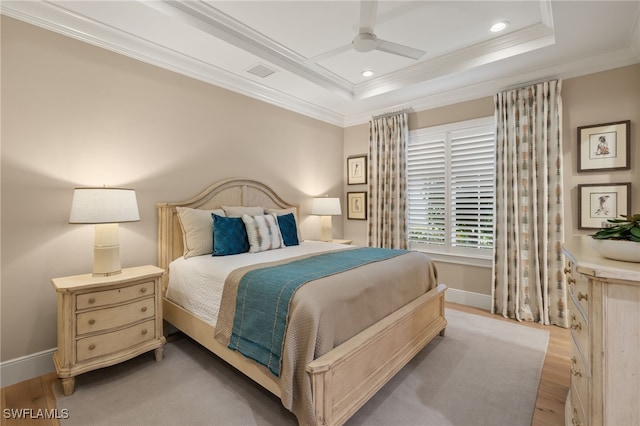 bedroom featuring a raised ceiling, ceiling fan, light wood-type flooring, and ornamental molding