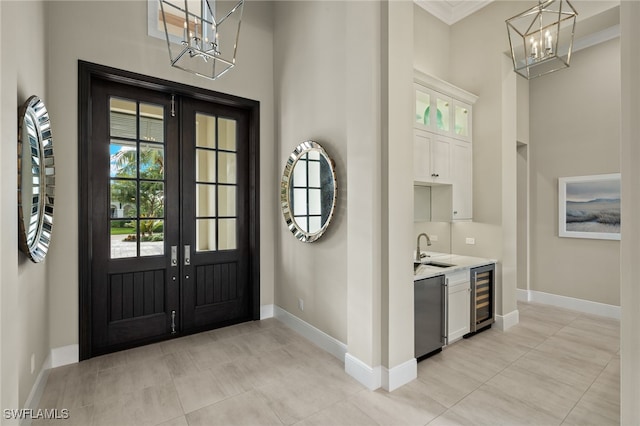 foyer entrance featuring french doors, ornamental molding, beverage cooler, sink, and light tile patterned flooring