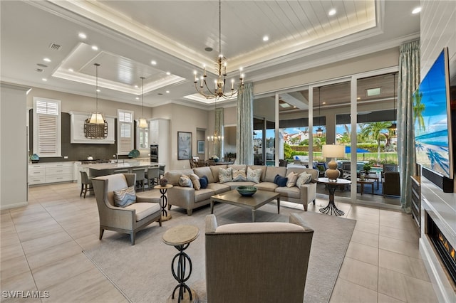 living room with a chandelier, a raised ceiling, and ornamental molding