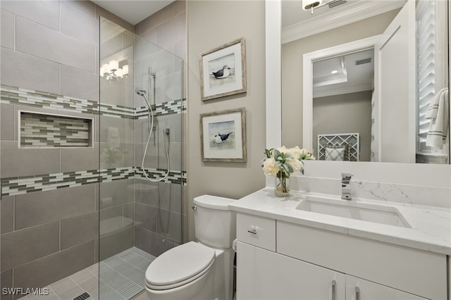 bathroom featuring a tile shower, vanity, toilet, and ornamental molding