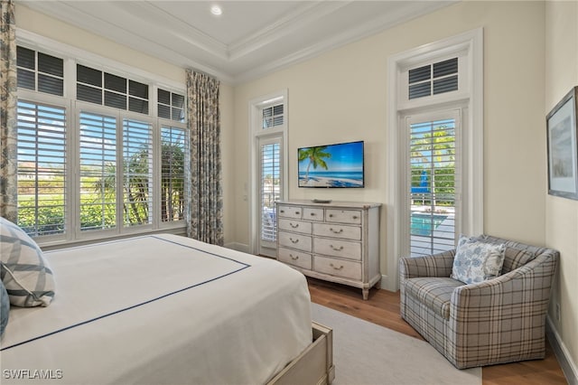 bedroom featuring hardwood / wood-style floors, ornamental molding, and a tray ceiling