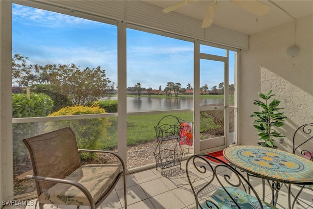 sunroom / solarium with ceiling fan and a water view