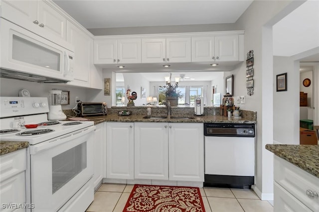 kitchen with white cabinets, light tile patterned floors, white appliances, and dark stone counters