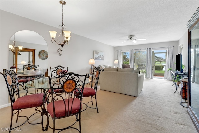 carpeted dining space with a textured ceiling and ceiling fan with notable chandelier