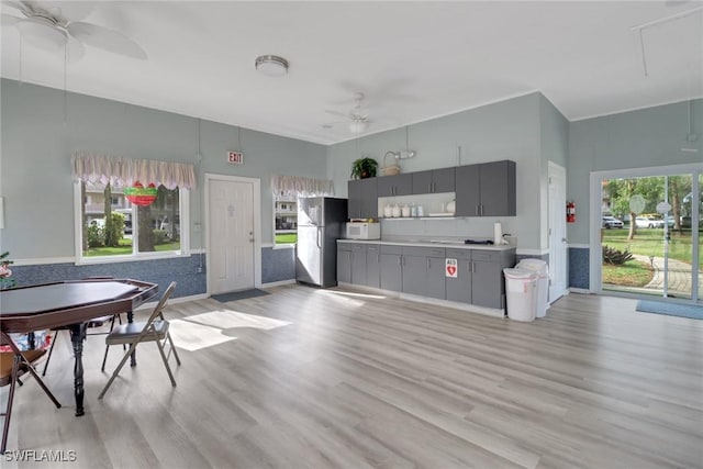 kitchen featuring stainless steel fridge, gray cabinets, light hardwood / wood-style flooring, and ceiling fan