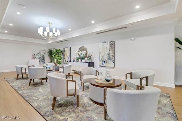 living room featuring a raised ceiling, crown molding, light hardwood / wood-style floors, and a notable chandelier