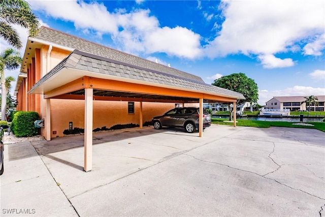 view of parking / parking lot with a water view and a carport