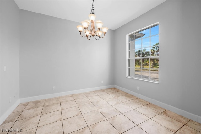 tiled spare room with an inviting chandelier