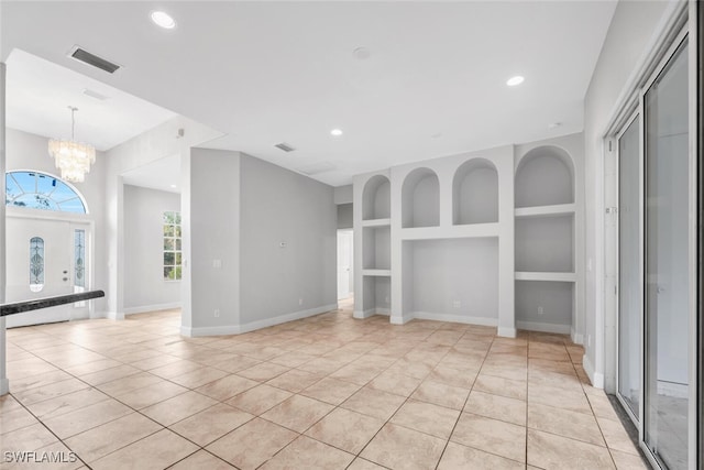 unfurnished living room with built in features, light tile patterned flooring, and an inviting chandelier