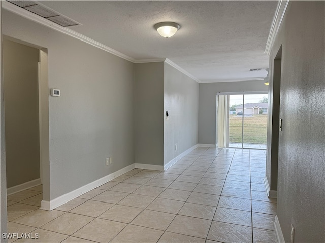 empty room with a textured ceiling, light tile patterned floors, and crown molding