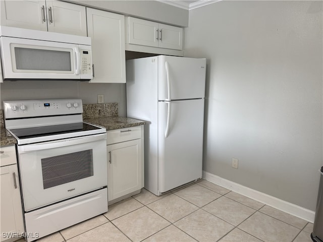 kitchen with white cabinetry, dark stone countertops, crown molding, white appliances, and light tile patterned floors