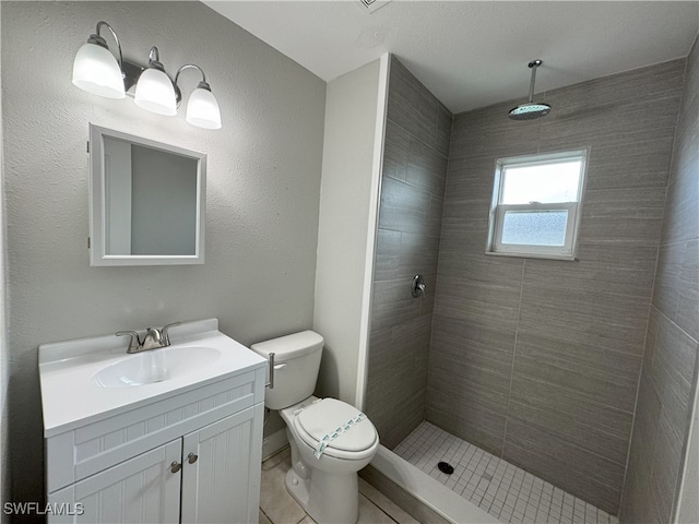 bathroom featuring tiled shower, vanity, toilet, and tile patterned flooring