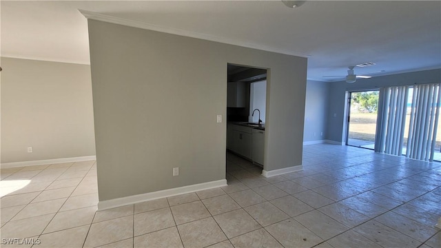 tiled empty room featuring ceiling fan, crown molding, and sink