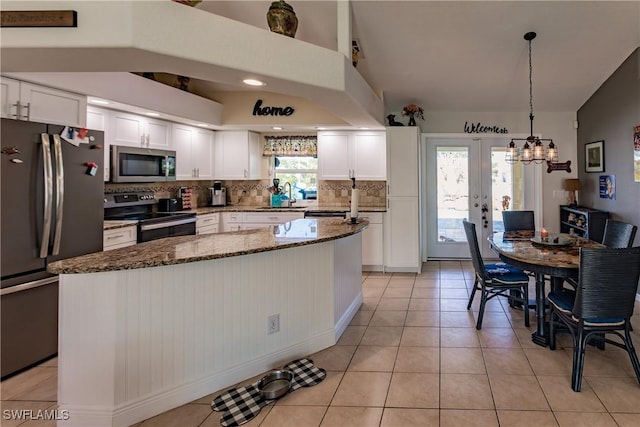 kitchen with a center island, white cabinets, dark stone countertops, tasteful backsplash, and stainless steel appliances