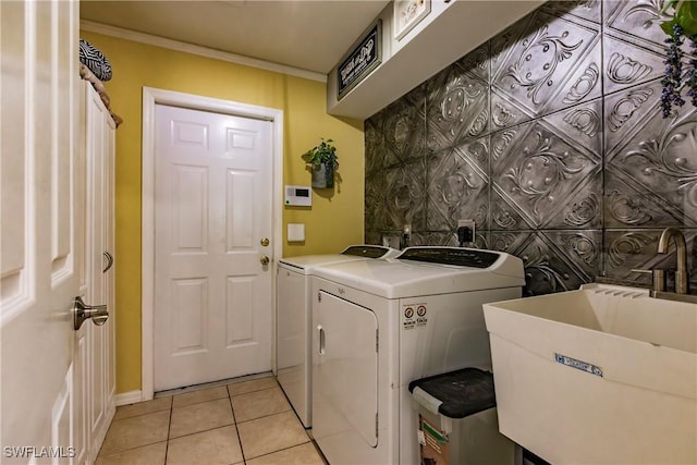 laundry area featuring washing machine and dryer, crown molding, sink, and light tile patterned floors