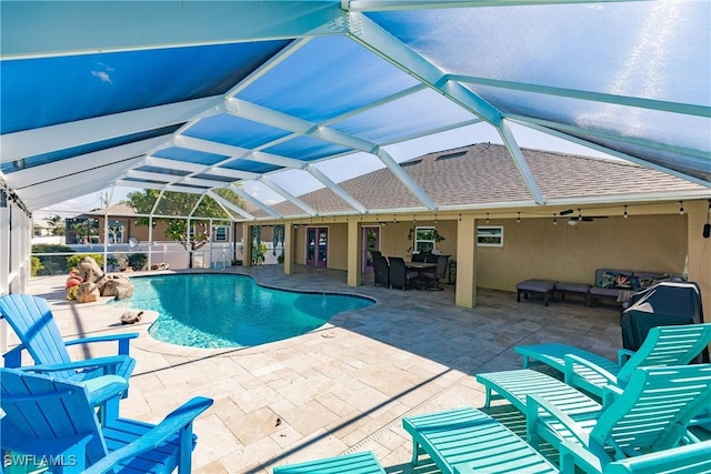 view of swimming pool featuring glass enclosure, ceiling fan, a patio, and an outdoor hangout area