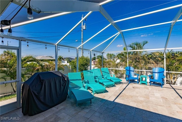 view of patio with area for grilling and a lanai