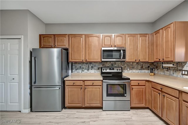 kitchen with stainless steel appliances, light hardwood / wood-style flooring, and tasteful backsplash