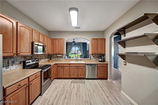 kitchen featuring sink, ceiling fan, appliances with stainless steel finishes, tasteful backsplash, and light hardwood / wood-style floors