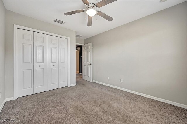 unfurnished bedroom with ceiling fan, light colored carpet, and a closet