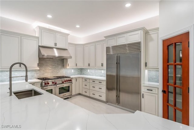 1160 8th St S, Naples, FL 34102 - kitchen with light stone counters, a sink, under cabinet range hood, high quality appliances, and backsplash