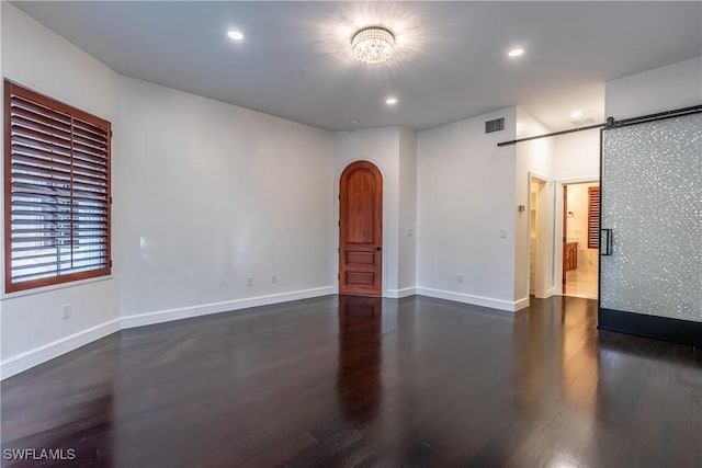 1160 8th St S, Naples, FL 34102 - spare room featuring wood finished floors, visible vents, baseboards, arched walkways, and a barn door