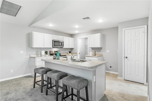 kitchen featuring a breakfast bar, a kitchen island with sink, white cabinets, sink, and stainless steel appliances