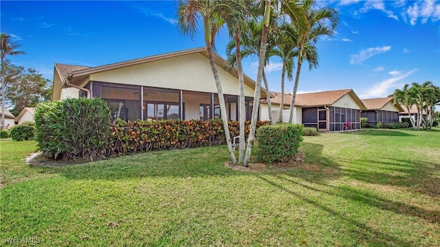 rear view of property with a lawn and a sunroom