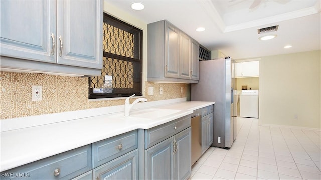 kitchen with gray cabinetry, sink, washer and clothes dryer, and stainless steel appliances