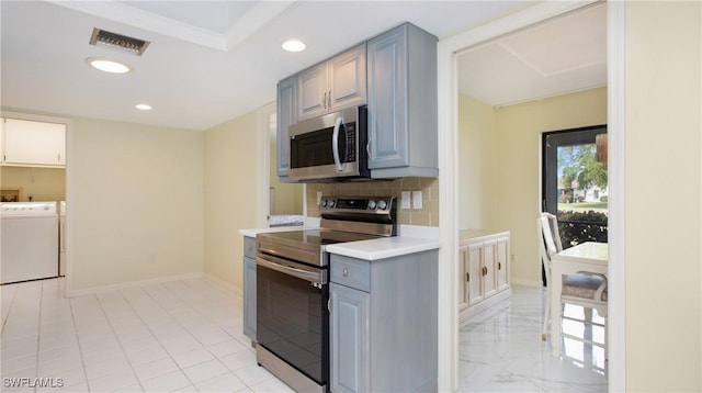 kitchen with gray cabinetry, washer and clothes dryer, ornamental molding, and appliances with stainless steel finishes