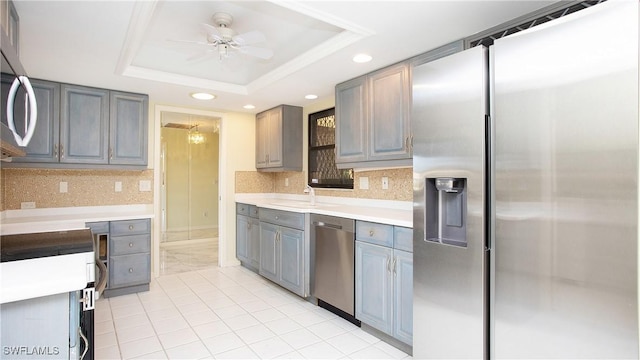 kitchen with stainless steel appliances, a raised ceiling, and gray cabinets