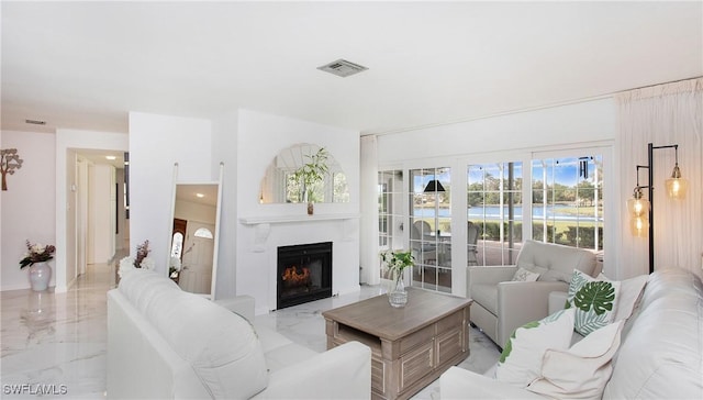 living area with a lit fireplace, marble finish floor, and visible vents