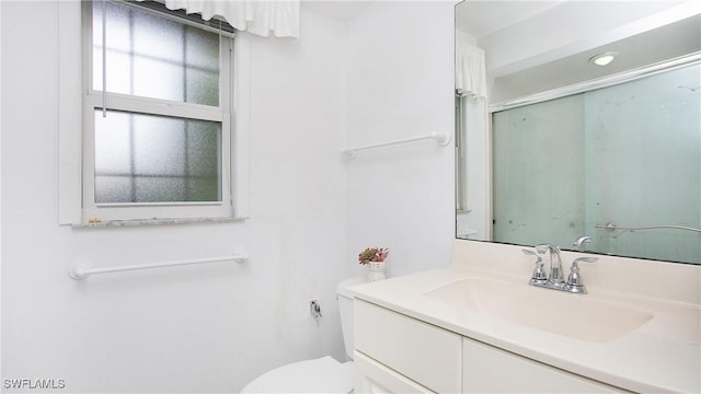 bathroom featuring vanity, toilet, and a shower with shower door