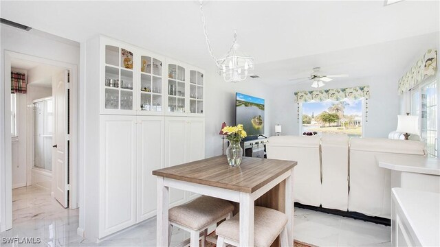 dining space with ceiling fan with notable chandelier